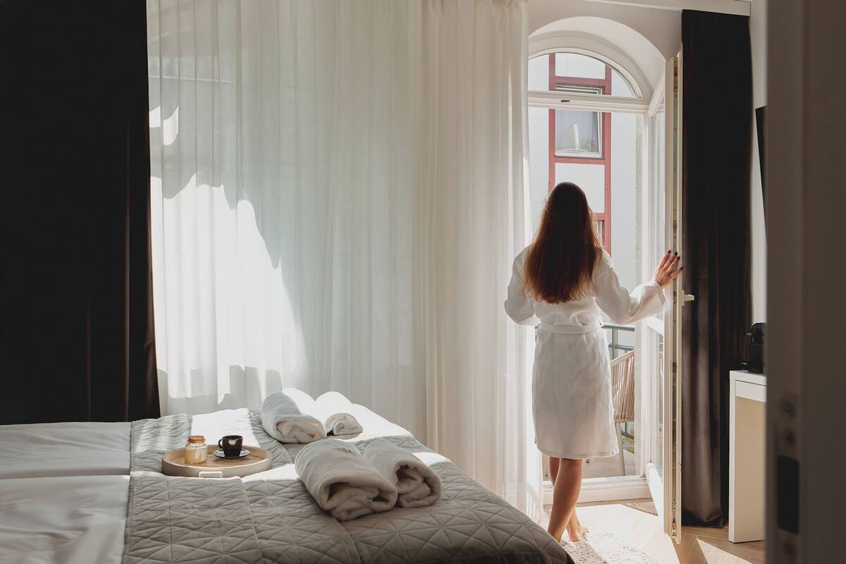 A hotel room with a bed, a tray with a cup and a bottle, and towels.