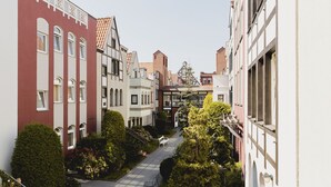 A narrow street with buildings on both sides, a bench, and a tree in the center. - Stągiewna Residence by Downtown Apartments (Gdansk)
