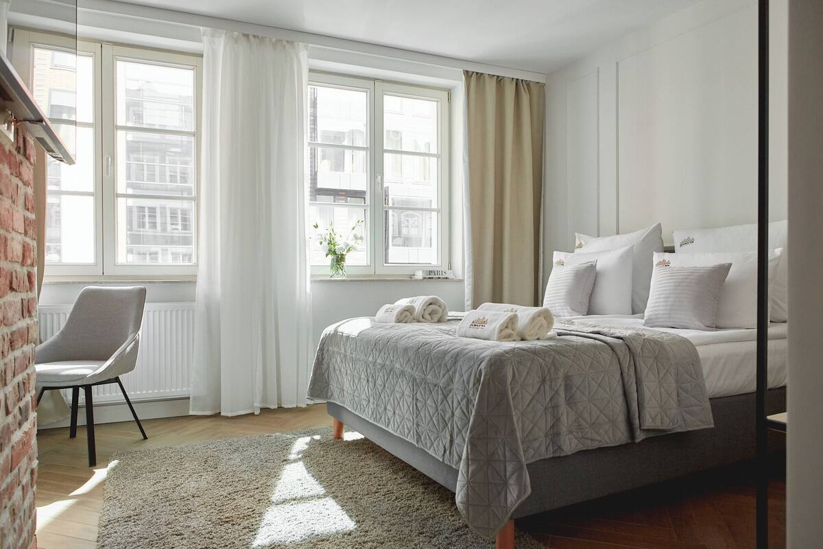 A bedroom with a bed, a chair, and a window with curtains.