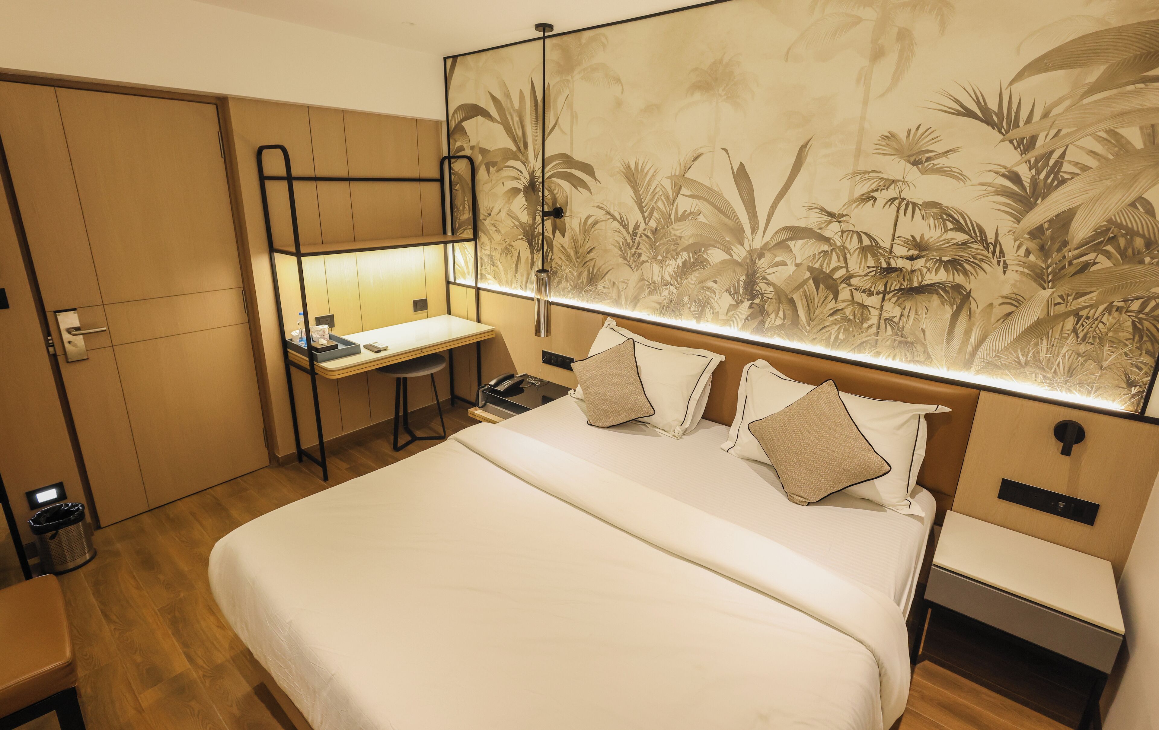 A hotel room with a bed, a desk, a chair, and a wardrobe.