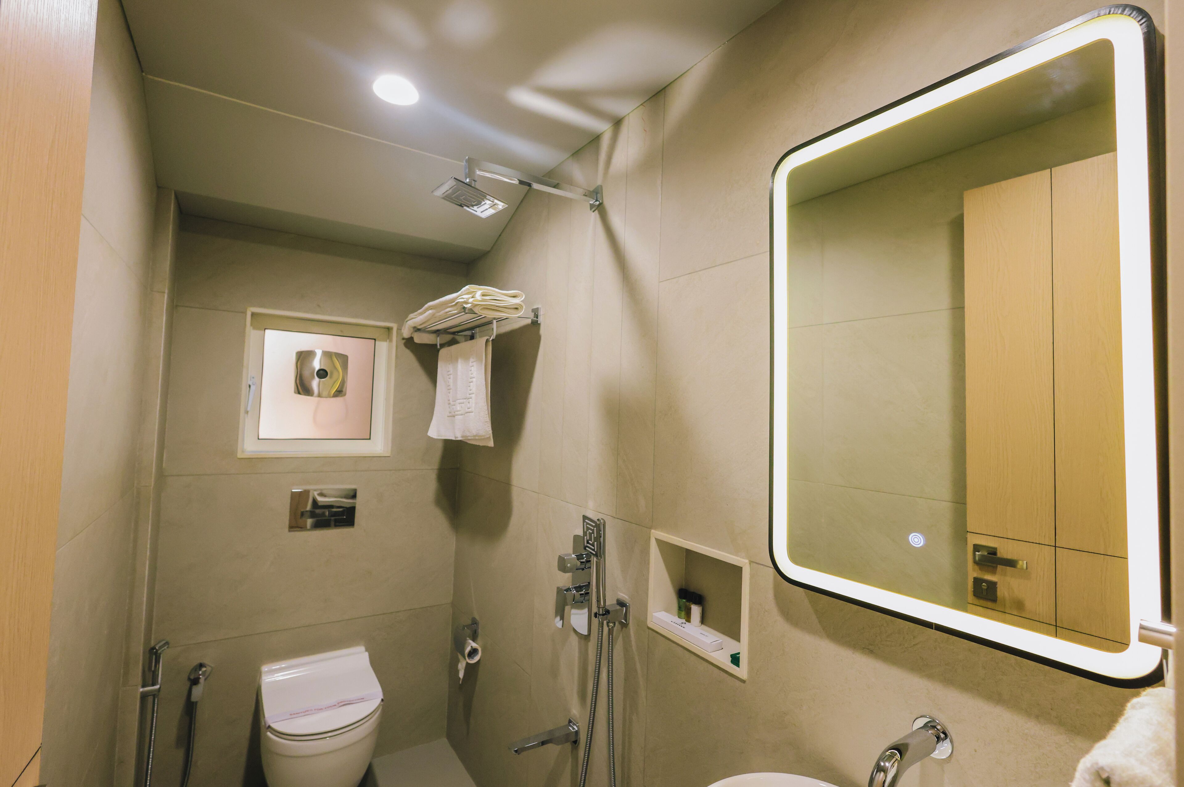 A bathroom with a toilet, a shower, a sink, a mirror, and a towel rack.