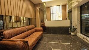 A modern lobby with a leather sofa, marble flooring, and a large window with a view. - Hotel Western (Mumbai)