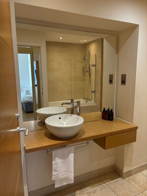 Un baño moderno con lavamanos doble, un espejo grande y una ducha.