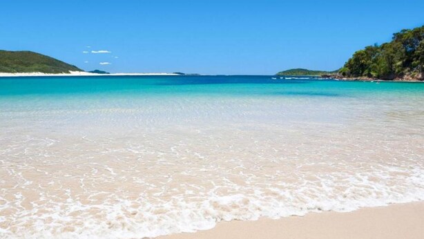 Ein Strand mit klarem türkisblauem Wasser und weißem Sand.