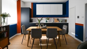 A modern kitchen with white cabinets, a wooden dining table, and two chairs.