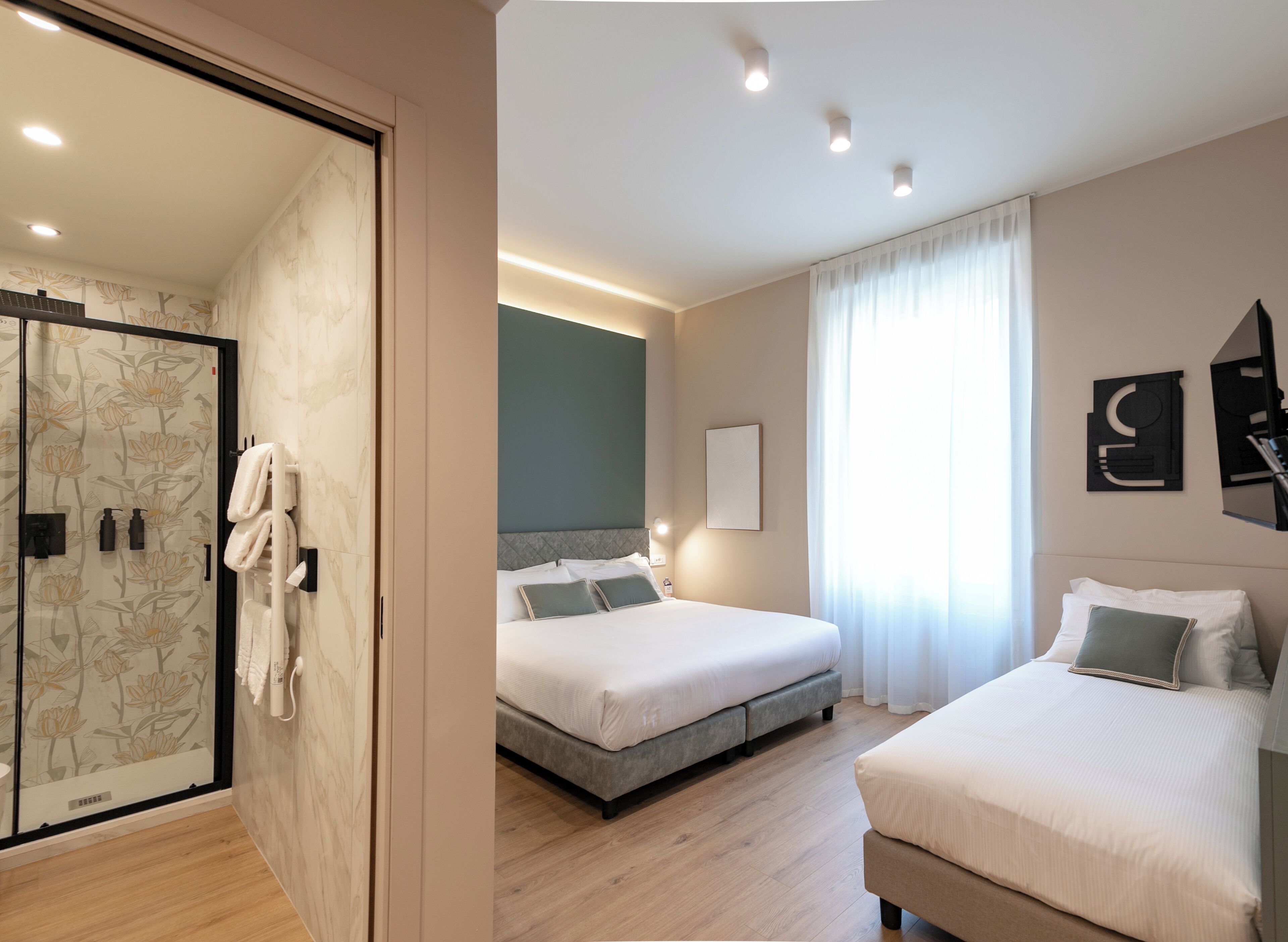 Ein Hotelzimmer mit Duschbereich, zwei Betten, einem großen Fenster mit Vorhängen und einem Wandbild.