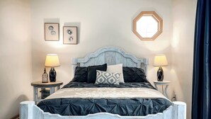 Un dormitorio con cama, dos mesitas de noche y una ventana con cortinas.