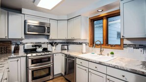 Una cocina moderna con armarios blancos, electrodomésticos de acero inoxidable y un alféizar de madera.