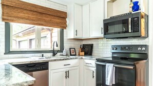 Une cuisine moderne avec des meubles blancs, un lave-vaisselle, un four à micro-ondes et un four traditionnel.