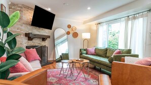 Un salon avec une cheminée, un canapé vert, une table basse en bois et un grand miroir.