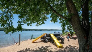 Een strand met een bandglijbaan en een picknickplaats aan het water.