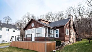 Une cabane en rondins avec une terrasse en bois et une cheminée en pierre.