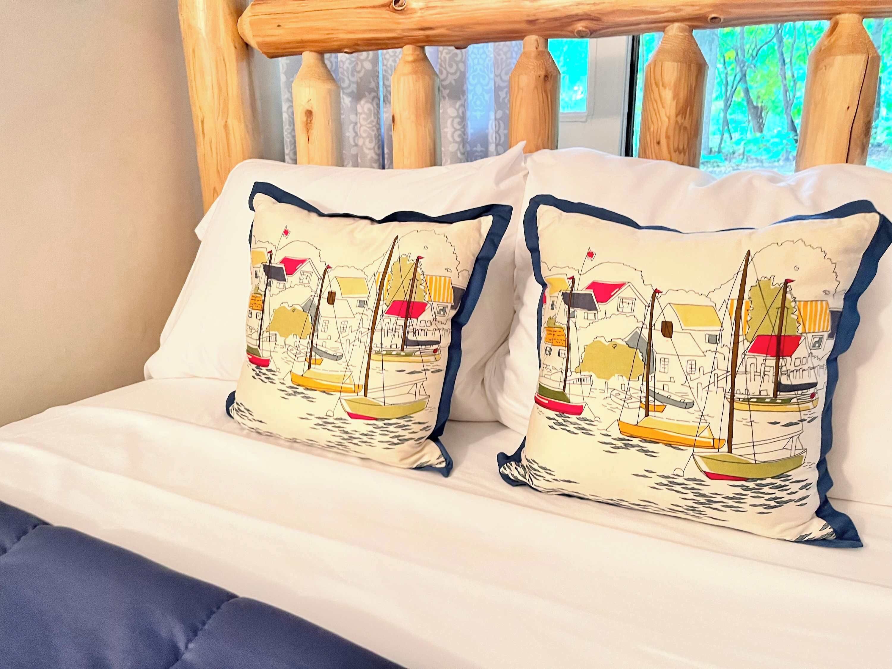 A bed with white bedding and two pillows featuring a nautical theme.