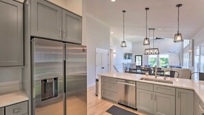 A modern kitchen with stainless steel appliances, grey cabinetry, and pendant lighting.