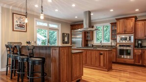 Une cuisine spacieuse dotée de meubles en bois, d’appareils électroménagers en acier inoxydable et d’un grand îlot central avec des tabourets de bar.