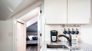 A kitchen with a coffee maker, a sink, and a sign above the cabinets. - The Hideaway at Hayloft Lodge – Chic & Unique Stay (Lake Geneva)