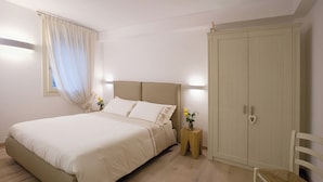 Un dormitorio con cama, mesitas de noche, armario y una silla.