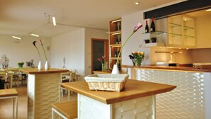 Una cocina moderna con encimeras de madera, un espacio para vinos empotrado y una zona de estar con una cesta de mimbre.