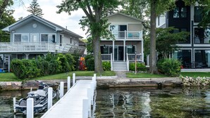 Une propriété située au bord de l’eau, dotée d’un quai, d’une maison avec balcon et d’un bâtiment moderne.