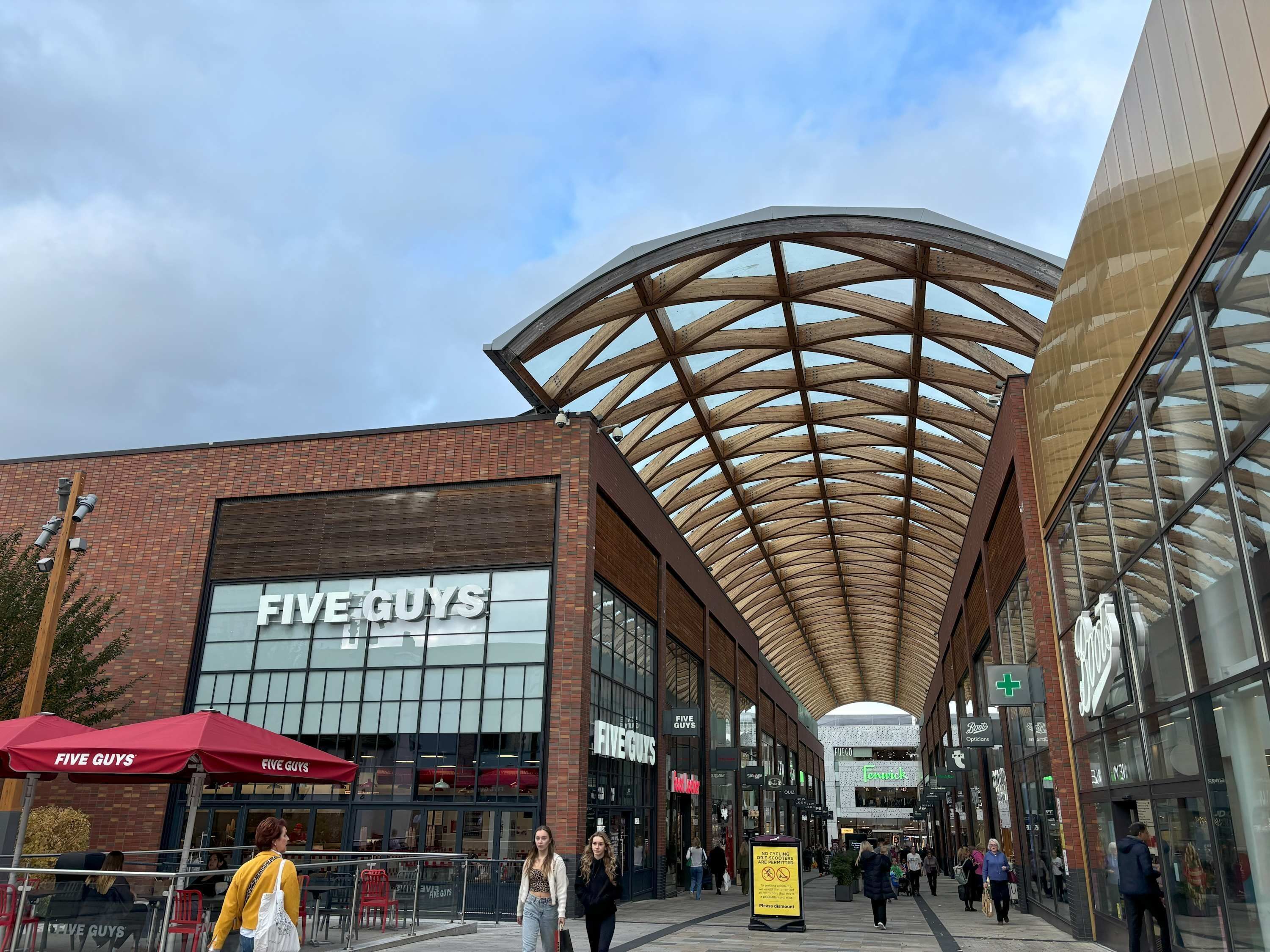 A modern shopping center with a prominent 'Five Guys' restaurant.