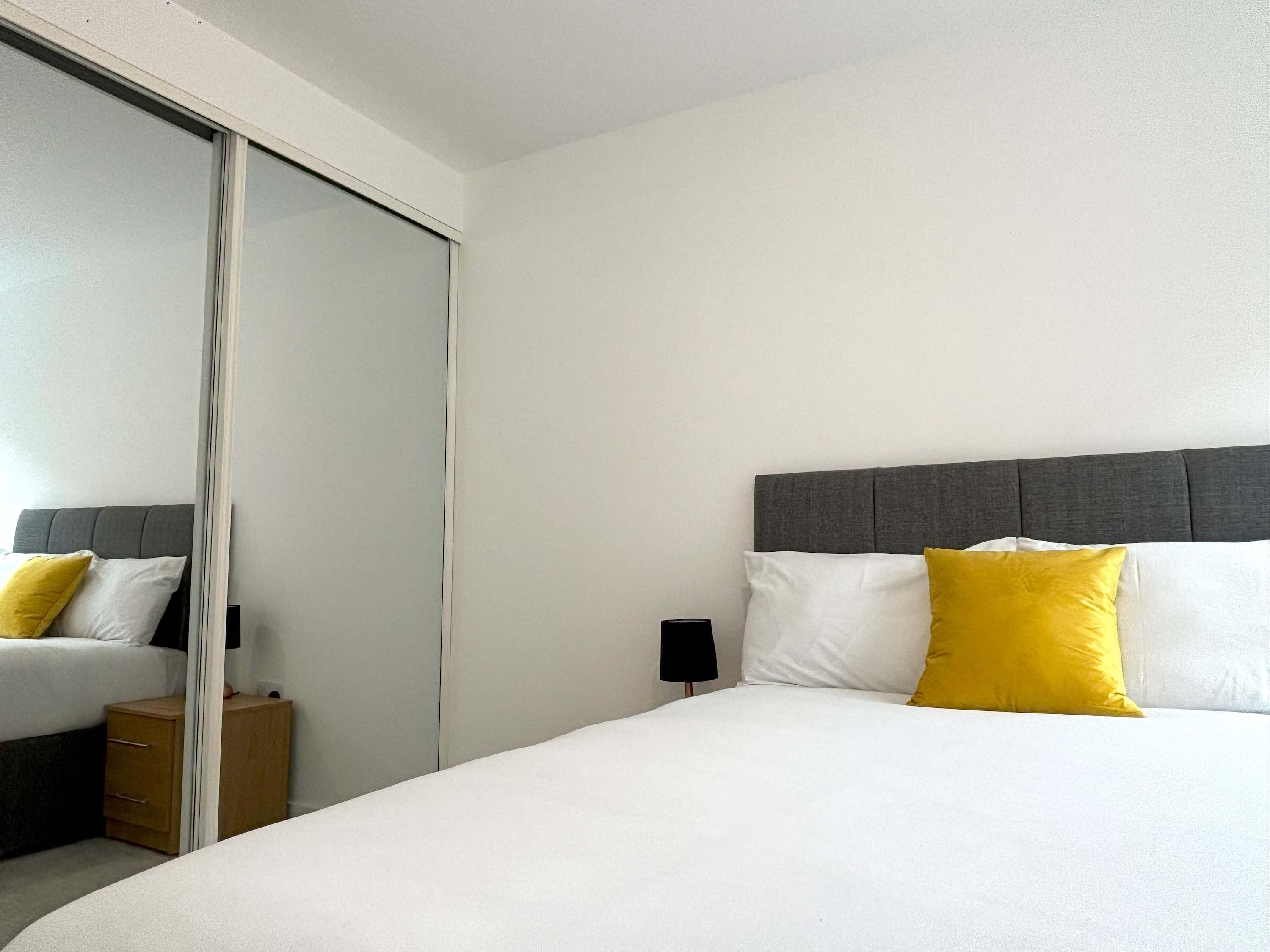 Una habitación de hotel con cama, mesita de noche, lámpara y puerta corredera.