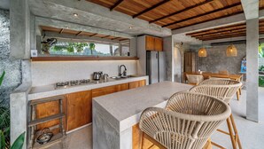 A modern kitchen with a large island, wooden ceiling beams, and a view of greenery outside. - Sola Villa Ubud - 2 Bedrooms (Ubud)