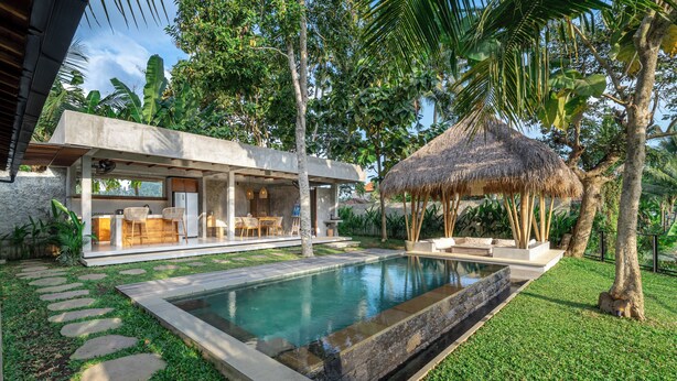 A modern outdoor pool area with a concrete deck, stone steps, and a thatched roof structure. - Sola Villa Ubud - 2 Bedrooms (Ubud)