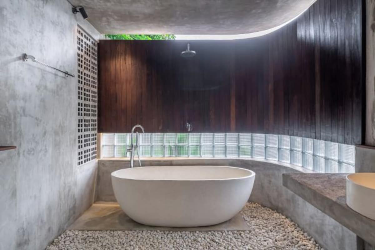 A modern bathroom with a freestanding bathtub, a showerhead, and a glass block wall.