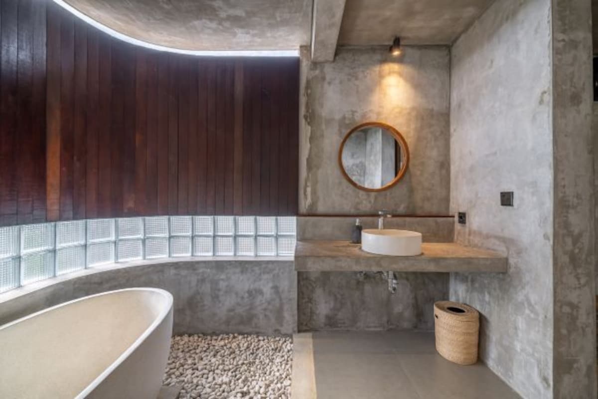 A modern bathroom with a freestanding bathtub, a round mirror, and a built-in sink.
