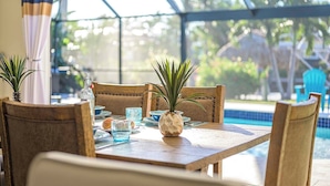 A dining table with chairs, a bottle, and a plant. - Serenity by the Gulf - Vesteva Vacation Rentals (Cape Coral)