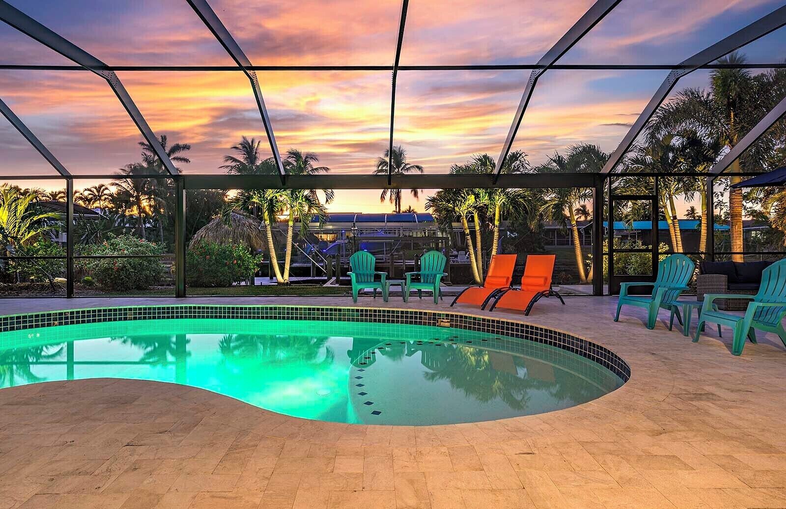 A swimming pool with a tiled edge, surrounded by lounge chairs and palm trees.