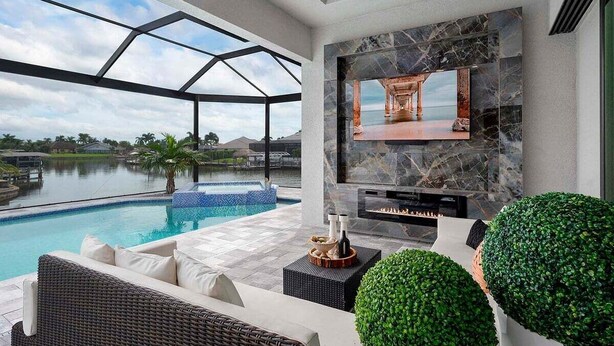 A modern outdoor living area with a pool, a fireplace, and a large TV screen.