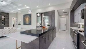 A modern kitchen with a central island, dark cabinetry, and pendant lighting.
