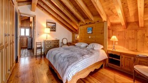 Ein Schlafzimmer einer Holzhütte mit Bett, Schminktisch und zwei Lampen.