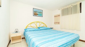 A bedroom with a bed, a nightstand, a window with curtains, and a wall-mounted picture.