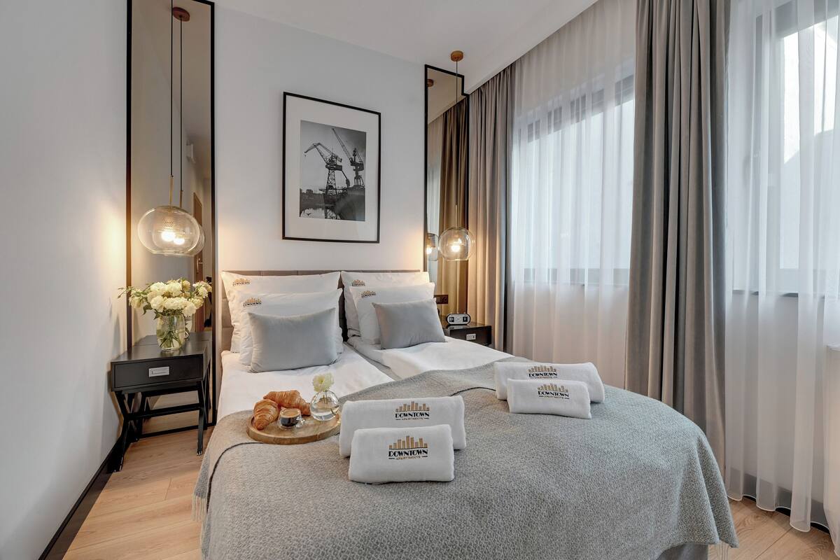 A hotel room with a neatly made bed, a bedside table with a vase of flowers, and a framed picture on the wall.
