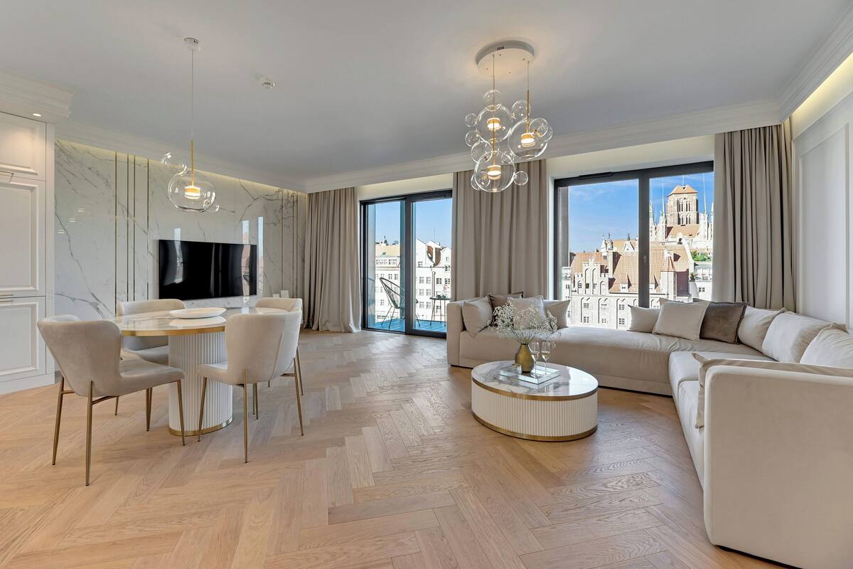 A modern living room with a dining area, large windows with a city view, and a sofa.