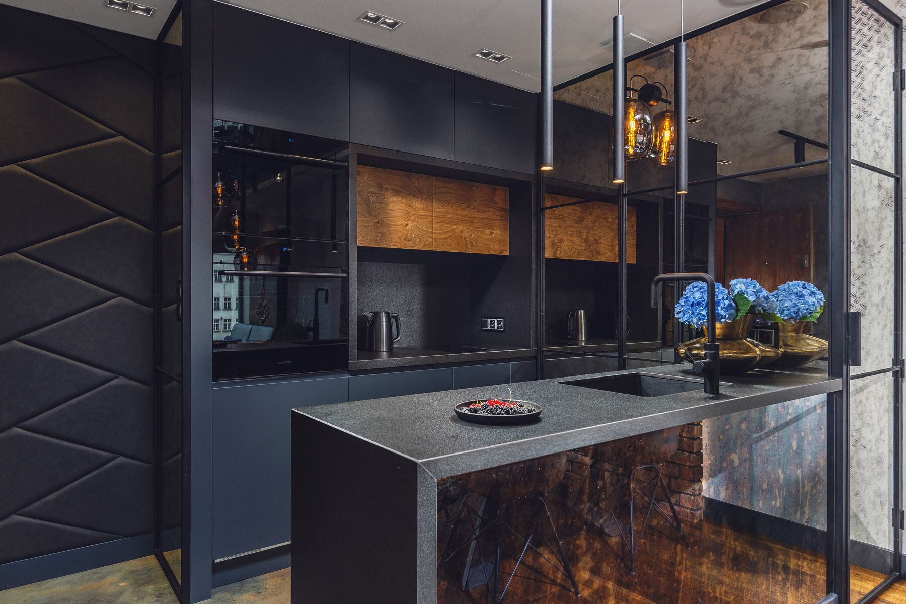 A modern kitchen with dark cabinetry, a marble countertop, and a built-in stove.