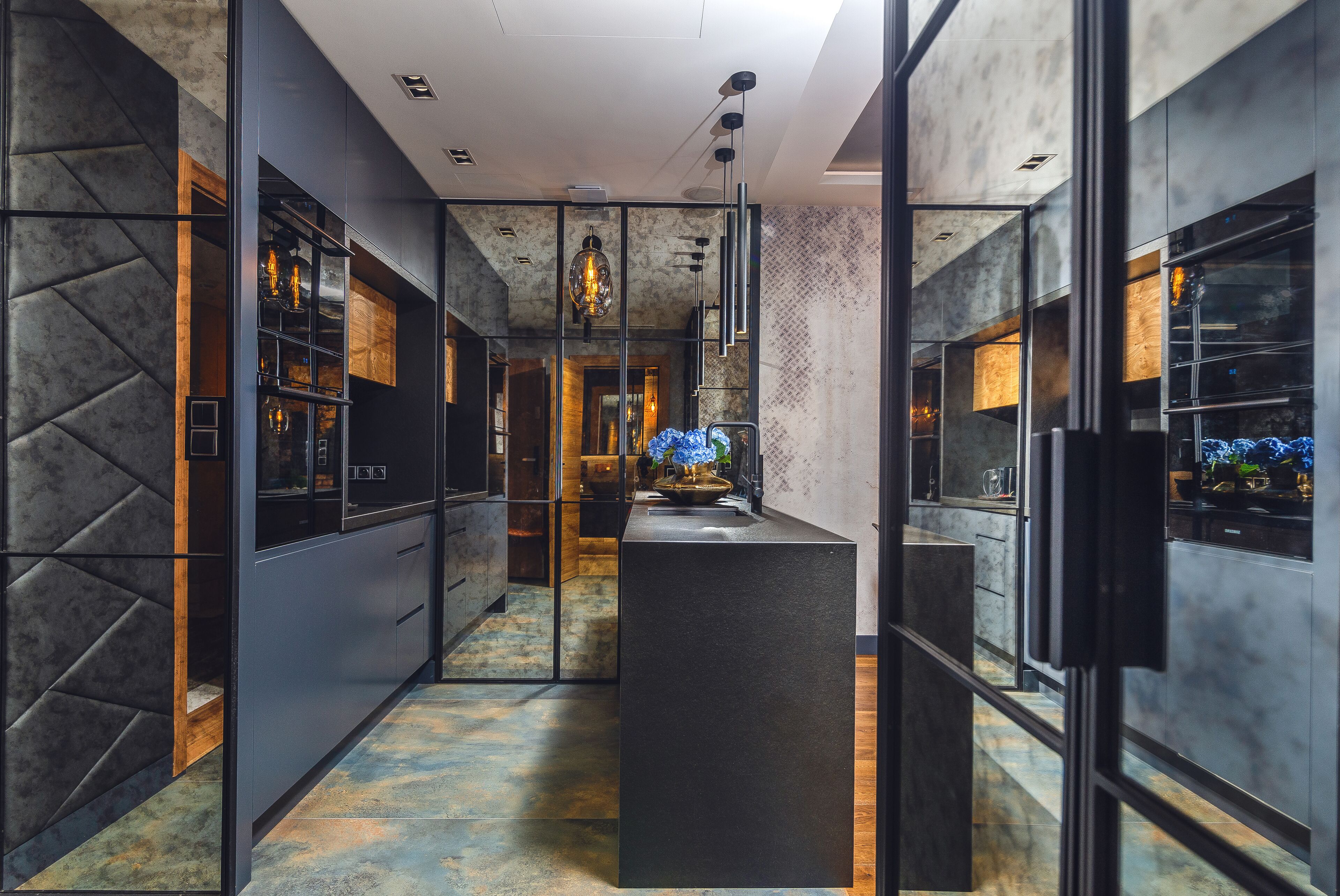 A modern kitchen with dark cabinetry, a central island, and pendant lighting.