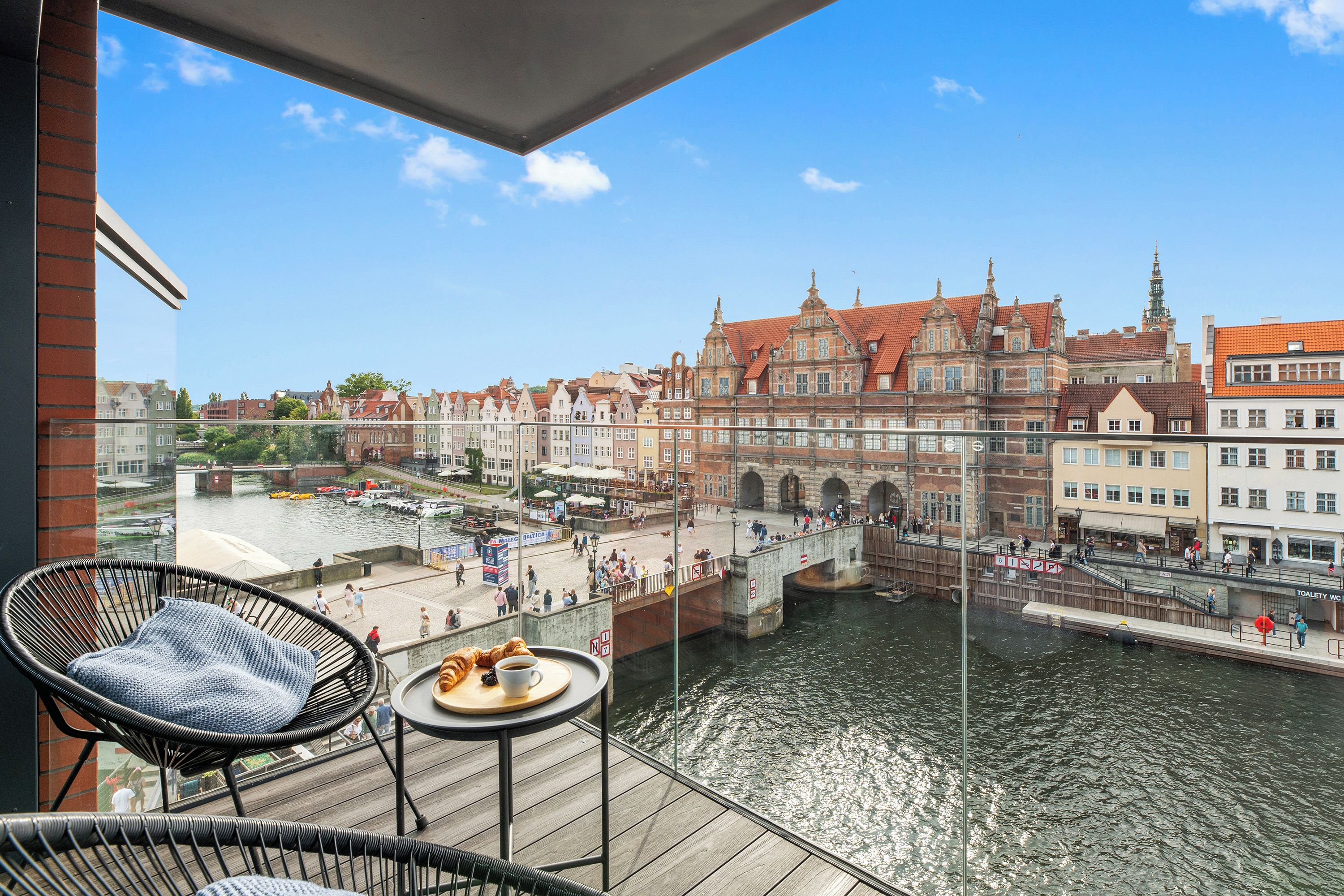 A balcony with a view of a river, a bridge, and historic buildings.