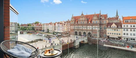 Un balcon offrant une vue sur une rivière, un pont et des bâtiments historiques.