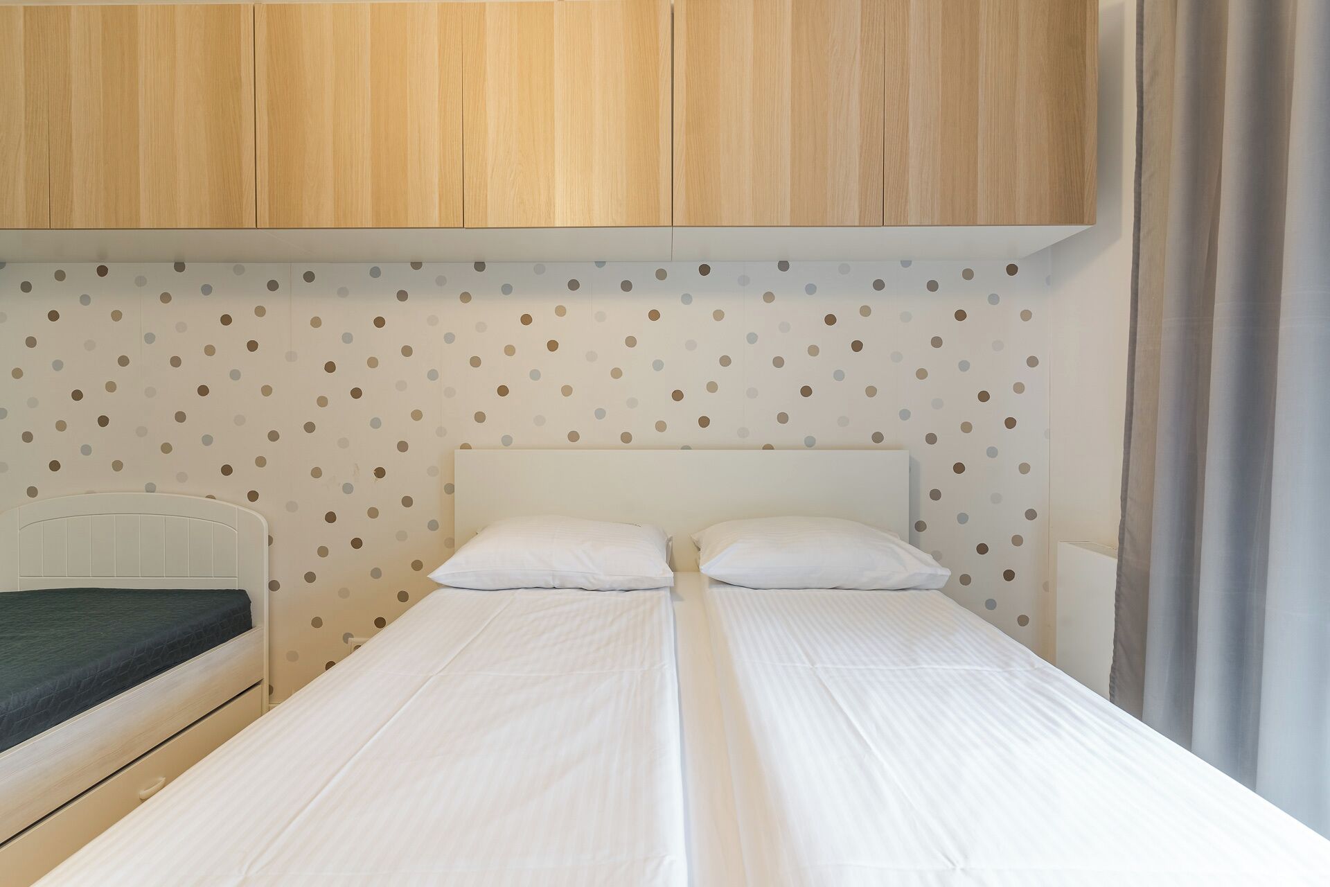 A bedroom with a bed, two pillows, and a wooden wardrobe.