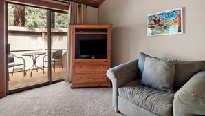 Una sala de estar con un aparador de madera, un televisor, un sofá gris y un cuadro en la pared.