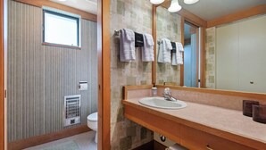 Un baño con tocador de madera, un espejo grande y toallas colgadas en un perchero.