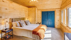 Ein Schlafzimmer einer Holzhütte mit einem Bett, einem Nachttisch und einer blauen Tür.