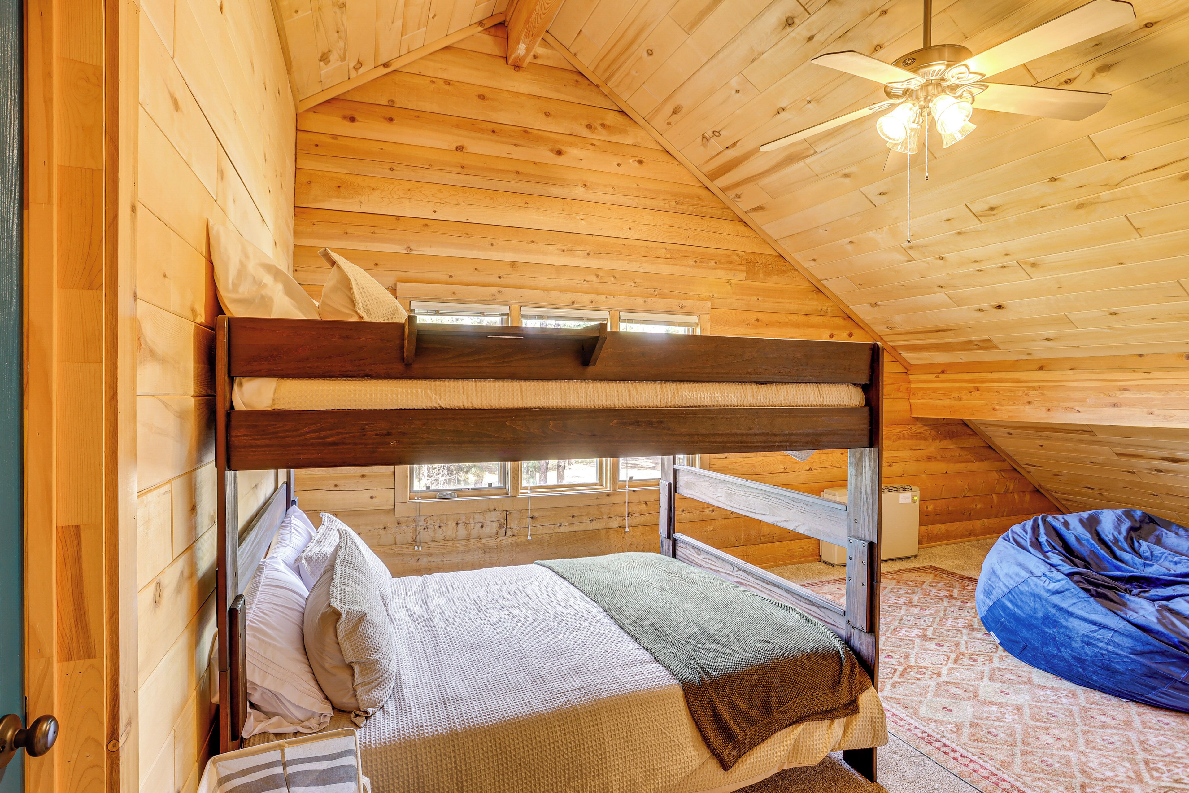 A bunk bed in a wooden cabin room with a ceiling fan and a bean bag chair.