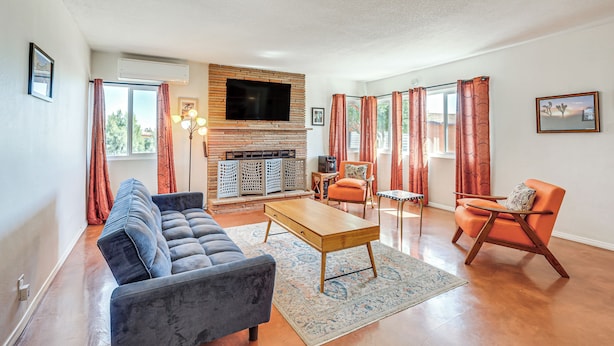 A living room with a sofa, a wooden coffee table, and a television mounted on a brick wall.
