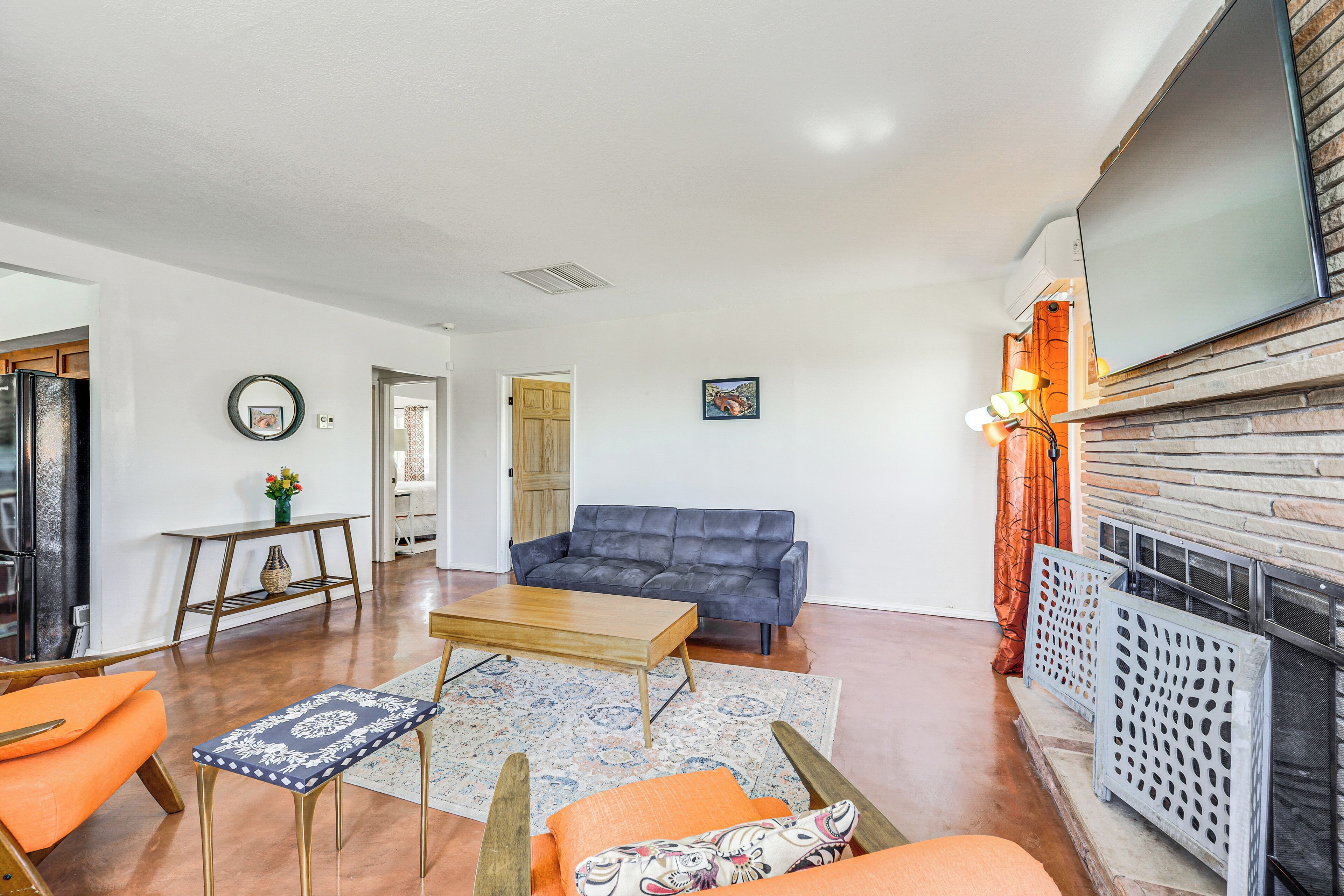 A living room with a sofa, coffee table, and chairs. There is a fireplace and a television mounted on the wall.