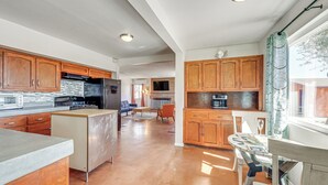 A spacious kitchen with wooden cabinets, a central island, and a dining area with a table and chairs.