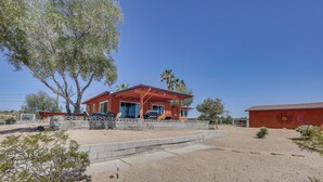 A red building with a covered porch, a tree in front, and a clear blue sky.